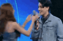 a man and a woman are talking into microphones .