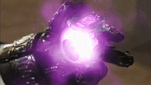 a person in a black glove is holding a purple object with a green light coming out of it
