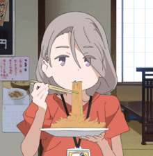 a girl with a lanyard around her neck is eating a plate of food with chopsticks