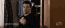 a man in a suit is standing in front of a closet .