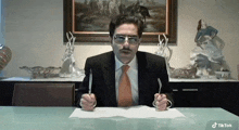 a man in a suit and tie is sitting at a table with a fork and knife