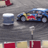 a racing car with a red bull on the side is driving on a track