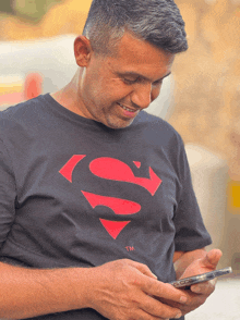 a man wearing a black superman t-shirt looks at his phone