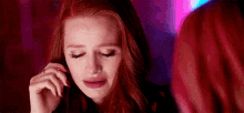 a woman with red hair is crying while looking at herself in the mirror .