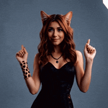 a woman in a black dress with cat ears is giving a thumbs up