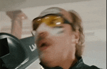a close up of a person wearing sunglasses and a hat .