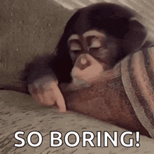 a chimpanzee is laying on a bed with its eyes closed and pointing at something .