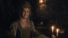 a woman in a green dress is sitting at a table with lit candles