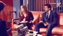 a man and a woman are sitting on a couch talking to a man