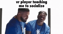 two men in blue shirts are sitting next to each other and one of them is teaching the other how to socialize .