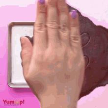 a person 's hand is pressing a heart shaped cookie dough into a pan with yum up written on the bottom