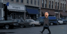 a man walking down a street in front of stone 's