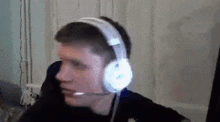 a man wearing headphones with a microphone is sitting in front of a computer .