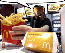 a person holding a container of french fries in front of a mcdonald 's box