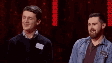 two men are standing next to each other on a stage and one of them is smiling .