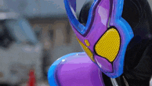 a purple and blue mask with a yellow eye