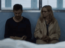 a man and a woman sit next to each other in a room