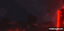 a red robot is holding a sword in the dark .