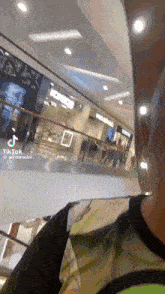 a man is walking down an escalator in a shopping mall