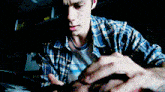 a man in a plaid shirt is looking at something in the dark