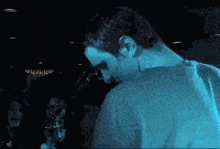 a man in a blue shirt stands in front of a crowd of people