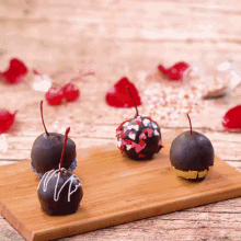 three chocolate covered cherries are sitting on a cutting board