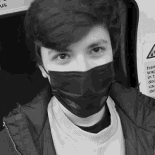 a black and white photo of a young man wearing a mask