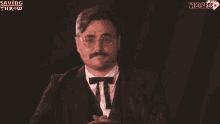a man with a mustache and glasses is wearing a tuxedo and bow tie