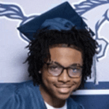 a young man is wearing a graduation cap and gown and glasses .