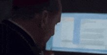 a man is looking at a computer screen in a dark room .