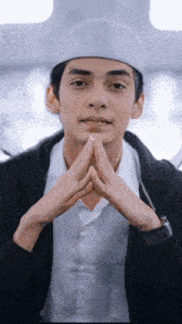 a man wearing a white hat with his hands folded