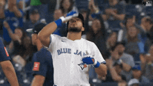 a man wearing a blue jays jersey looks up into the sky