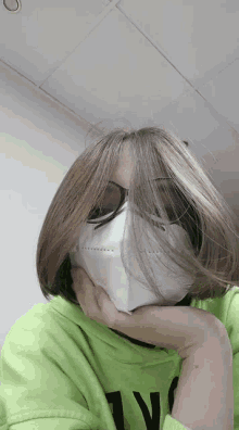 a woman wearing a mask and sunglasses holds her hand to her face .