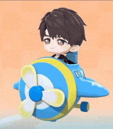 a boy is sitting in a blue and yellow airplane with a propeller .