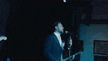 a man singing into a microphone in front of a blue background