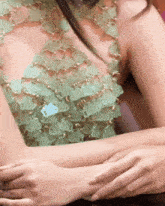 a close up of a woman 's arm with a green and gold top on