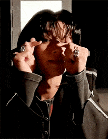 a person with rings on their fingers making a heart shape