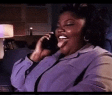 a woman is sitting on a couch talking on a cell phone .