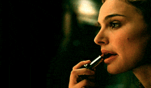 a woman is applying lipstick to her lips