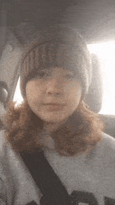 a woman wearing a beanie and a gray shirt with the letter n on it