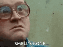 a man with glasses is making a funny face and saying `` smell 's gone '' .
