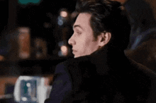 a man is smiling and saying `` hey trouble '' while sitting in a bar .