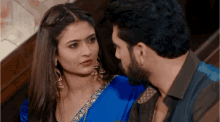 a man and woman are looking at each other and the woman is wearing a blue dress