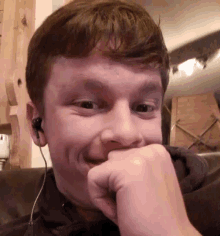 a man wearing ear buds is smiling and covering his mouth