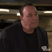 a close up of a man 's face with a shaved head wearing a bar rescue t-shirt .