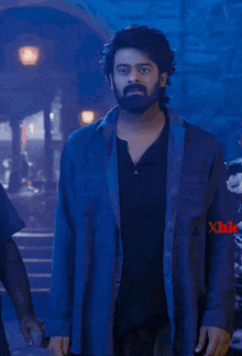 a man with a beard is wearing a black shirt with the letters xhk on his shoulder