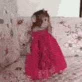 a monkey is wearing a pink dress and standing on a bed .