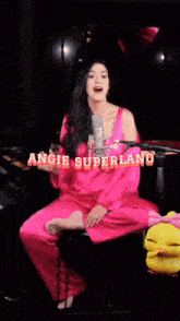a woman singing into a microphone with the name angie superlang on the bottom right