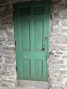 a green door in a stone wall with a lock