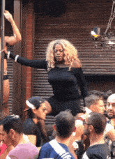 a woman in a black dress is standing on a pole in front of a crowd of people